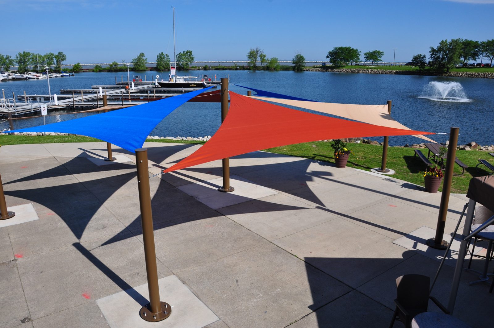 Steel posts bolted to concrete with base plates, holding triangle sails
