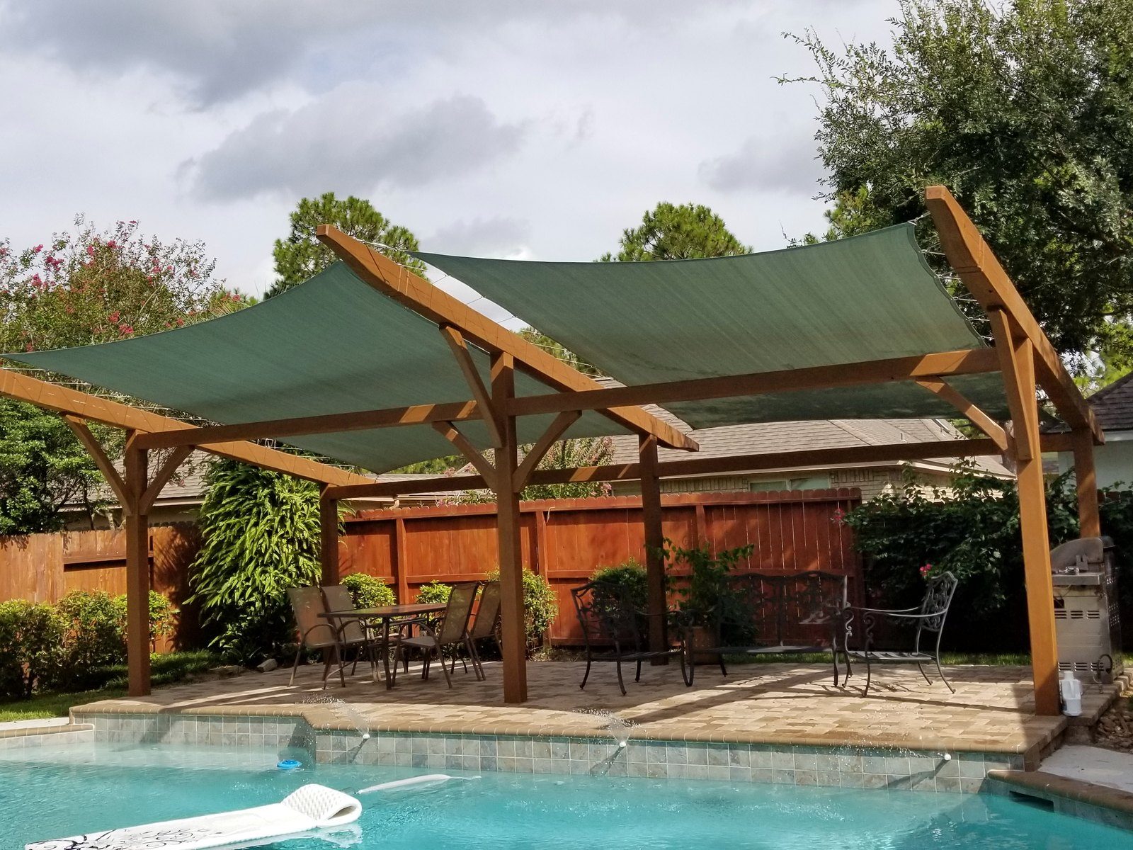 Green rectangle sails over a pool and pergola
