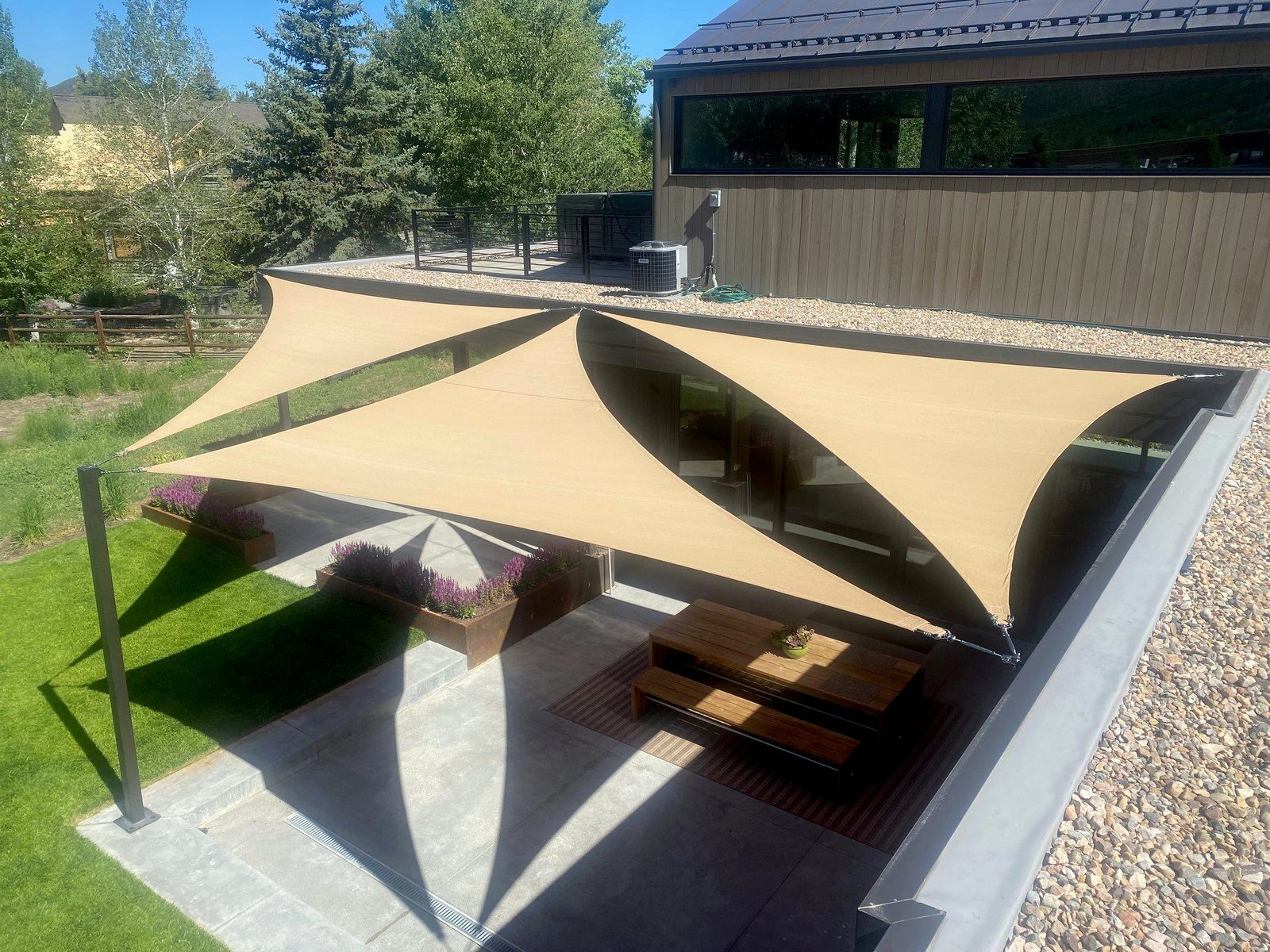 Overlapping tan triangle sails over a patio